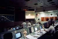 Several rows of consoles. A large screen showed a lunar lander