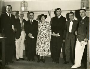 monochrome photograph of six men and a woman, standing