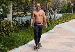 Tattoeed skateboarder riding on beach shirtless.jpg