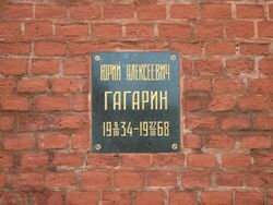 Plaque on a brick wall with inscription: Юрий Алексеевич Гагарин, 1934-03-09–1968-03-27