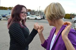 Two women link pinkies in a parking lot. One of them is Elizabeth Warren.