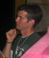 An approximately 34-year old man looking at something to the left of the camera.