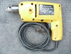 Yellow plastic household type electric drill with black coiled flexible cord