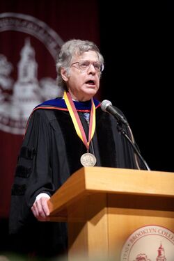 Levine stands at a lectern wearing academic robes and a medal