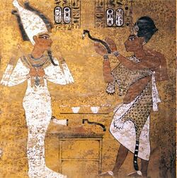 Fresco of a crowned man holding a curved stick-like implement in front of a man in mummy wrappings