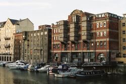 A large and complex reinforced concrete building with brick facing. Three large two-storey lucarnes in bare concrete extend from the wall above the harbour wharf.