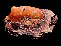 A specimen of recently mined Precious Mexican Fire Opal. The background host rock (matrix) has characteristic pink-white coloration.