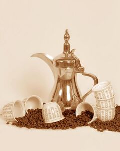 A dallah a traditional Arabic coffee pot with cups and coffee beans.jpg