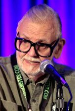 The image depicts horror director George A. Romero speaking at an event in Phoenix, Arizona.