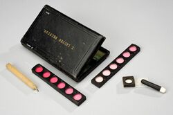 A black leather case with its contents: a candle and colour cards