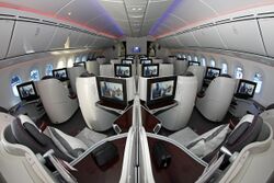 Airliner cabin with pod-like seats arranged in pairs or alone against the widewalls.