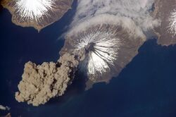A thick plume of dark ash arises from the volcano's cone.