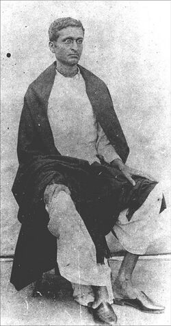 A photo of a sitting young Indian man wearing spectacles and looking to the right