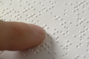 finger tip touching page with raised dots