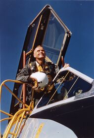 Photo of John Glenn leaning out of a cockpit looking into the distance