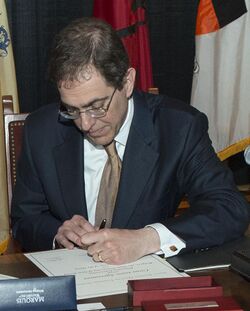 An image that shows Christopher Eisgruber signing a paper