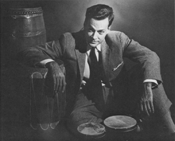 Feynman seated on the floor with drums around him