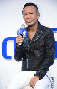 Toshihiro Nagoshi, seated, giving an interview.