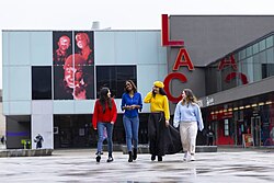 Four students walking in the courtyard space in front of the Lincoln Arts Centre.