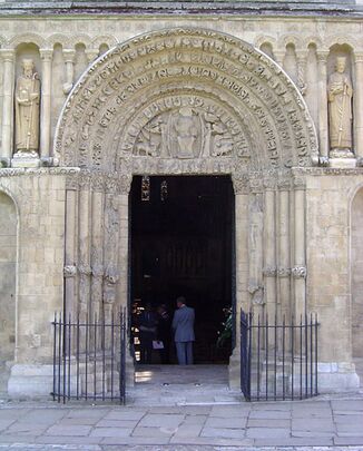 An ancient doorway has sculptured jambs and the figure of Christ within the arch over the lintel.