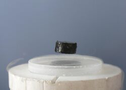 A magnet levitating over a superconducting material.