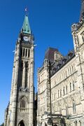 A tall, stone brick bell tower with a large clock in Ottawa, Canada