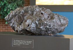 A piece of a gray meteorite on a pedestal