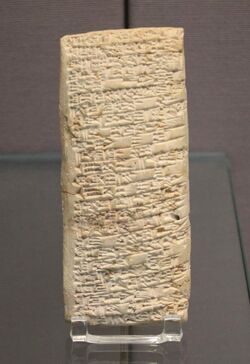 A long, rectangular tablet of sand-coloured clay, inscribed all over with cuneiform text.