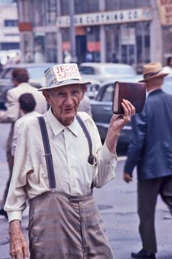 Man holding Bible and sporting Jesus Saves sign on his hat.jpg