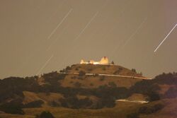 On top of Mount Hamilton, Lick Observatory sits while star trails suggests the movements of the night sky.