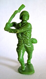 A green man holds up a shotgun, his body reflecting light via his pants, coat and chain.