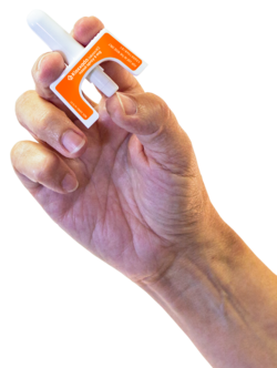 A hand holding a Kloxxado intranasal spray device. With the tip inserted into the nostril of someone who has suspected overdose, a dose of naloxone is administered by using one's thumb to push the plunger up toward the index and middle fingers.