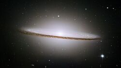 The dark band of the "dust lane" is clearly visible against the brighter background of stars within the Sombrero Galaxy.