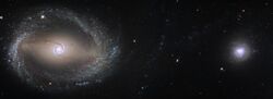 A larger spiral galaxy on left and smaller rounder galaxy on right in star field.