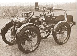 A sepia monotone image of motorized four wheeled vehicle built in 1898 by Royal Enfield.