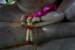 Flower offered in the hand of a Buddha image