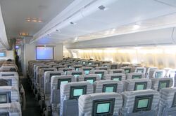 Interior view. Seats are separated by two aisles, in 3–4–3 configuration. A TV is positioned towards the front of aircraft.