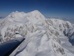 An aerial view of Denali; an airplane wing is visible in the lower-left corner