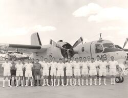 Black and white photograph of a large group of men wearing military uniforms posing in front of an aircraft