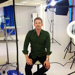 Dr Brad McKay sitting on stool in TV set