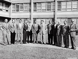 Black and white photograph of the twelve scientific specialists wearing suits and standing side by side. Karl Heimburg is third from the left.