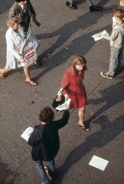 Without breaking stride, homeward bound commuter as the Staten Island Ferry Terminal reaches for leaflet from street... - NARA - 549907.jpg