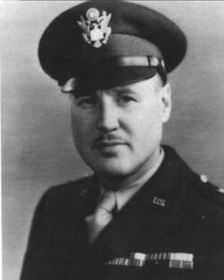 Head and shoulders of man in uniform with peaked cap and thin mustache.
