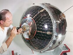 Scientist working on satellite using a tool on the presumed front of the craft
