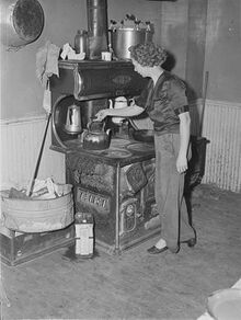 Metal can of motor oil next to wood burning stove and oven; used for getting the fire going; 1940