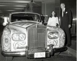 A woman and man stand beside John Lennon's psychedelically-painted Rolls Royce.