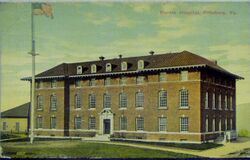 A color postcard showing a thee-and-a-half-story brick building with a pitched roof