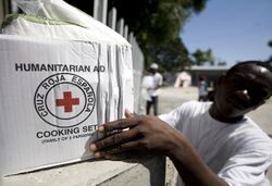 US Navy 100125-N-6266K-238 A Red Cross worker picks up a humanitarian box to give to an earthquake survivor in Port-au-Prince.jpg
