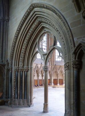 An elegant Gothic doorway opens into a chapter house. The arch of the doorway and the capital of its central pier have richly carved flowers.