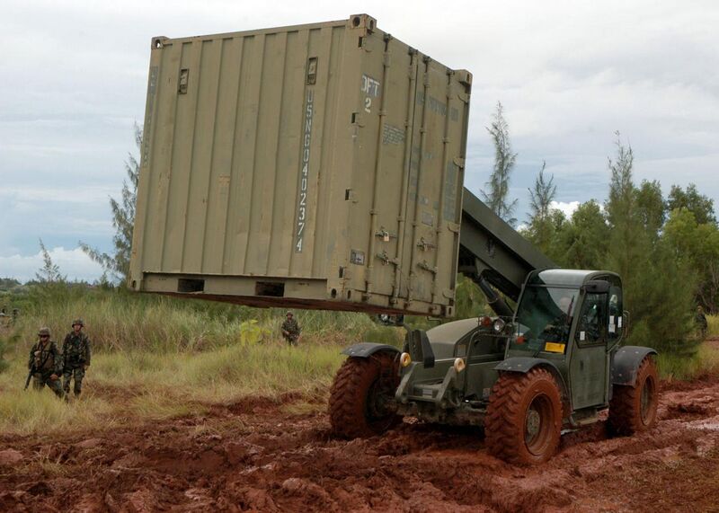 File:US Navy 070820-F-8678B-050 Construction Mechanic 1st Class Kenneth E. Terlaan drives a extendable boom forklift through the mud to position a CONEX box containing the field armory during setup for a field exercise.jpg